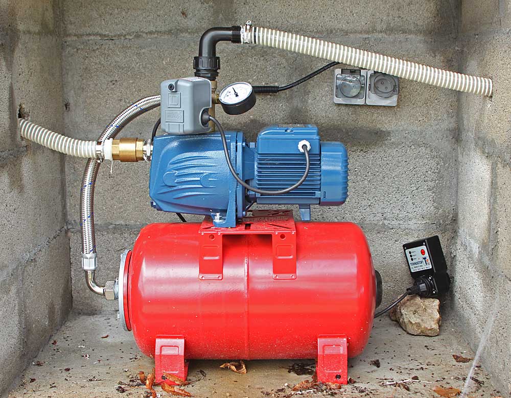 La pompe électrique en bleu et le ballon sous pression en rouge<br>A gauche arrivée de l'eau en provenance de la citerne<br>A droite connexion au tuyau d'arrosage